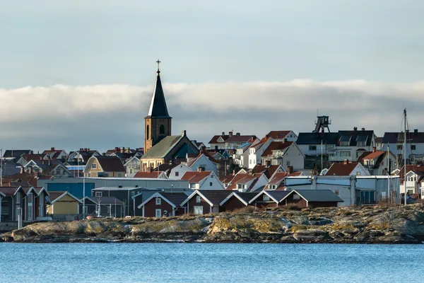 Kustsamhälle med kyrktorn och färgglada trähus vid havet